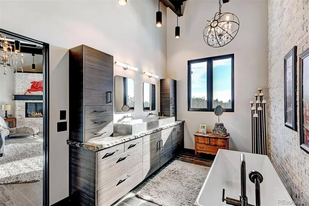 Primary bathroom with a large vanity and a soaking tub illuminated by a spherical chandelier.