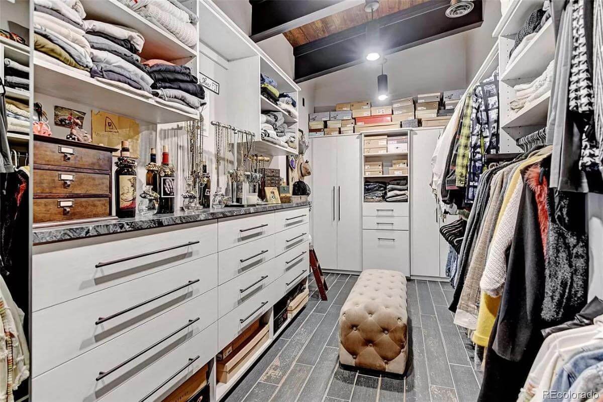 Her walk-in closet with white built-ins and a marble countertop.