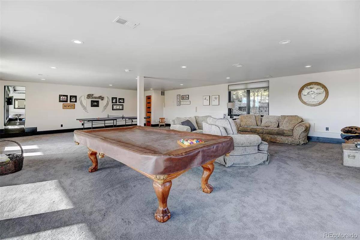 Game room with a billiards table and velvet sofas over the carpeted floor.