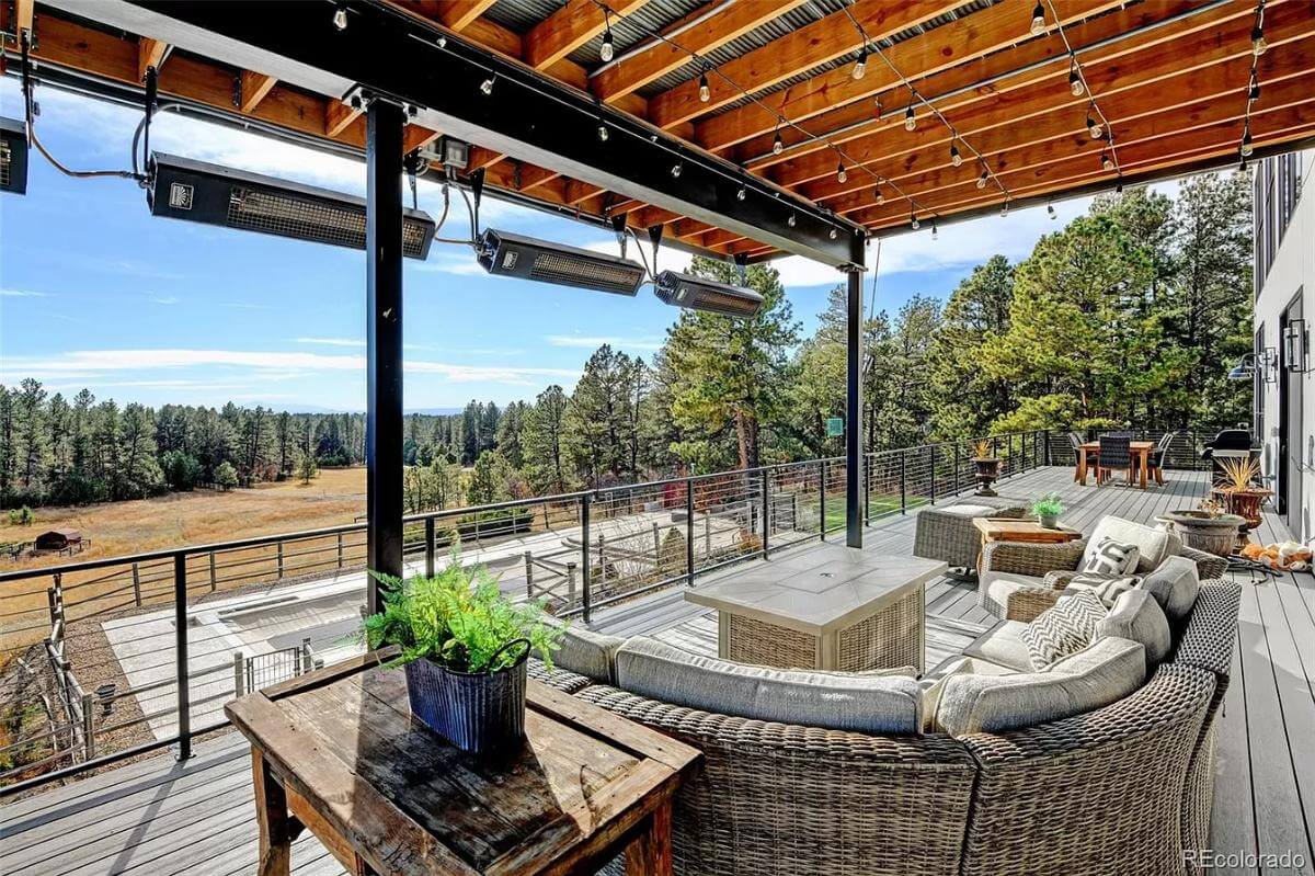 Rear deck with wicker sofas, rustic tables and an outdoor dining set.