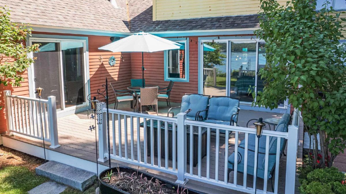 A deck with a table with an umbrella and chairs, a couch, and a coffee table.