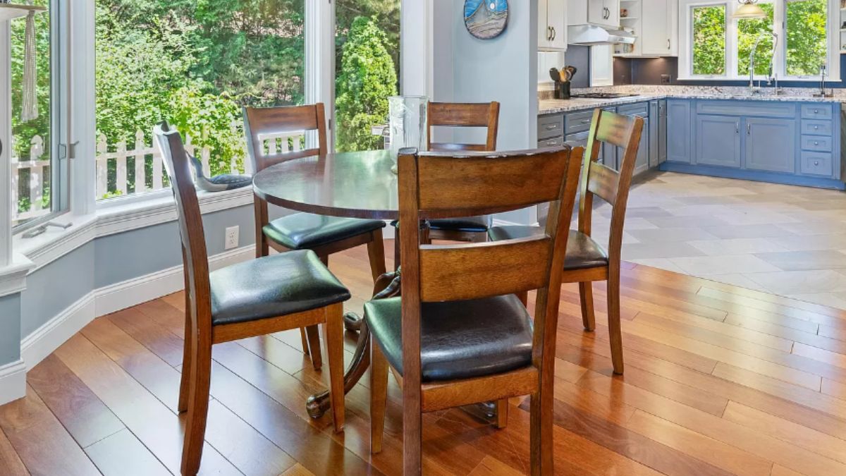 A dining area with wooden floors and a round dining table surrounded by chairs.