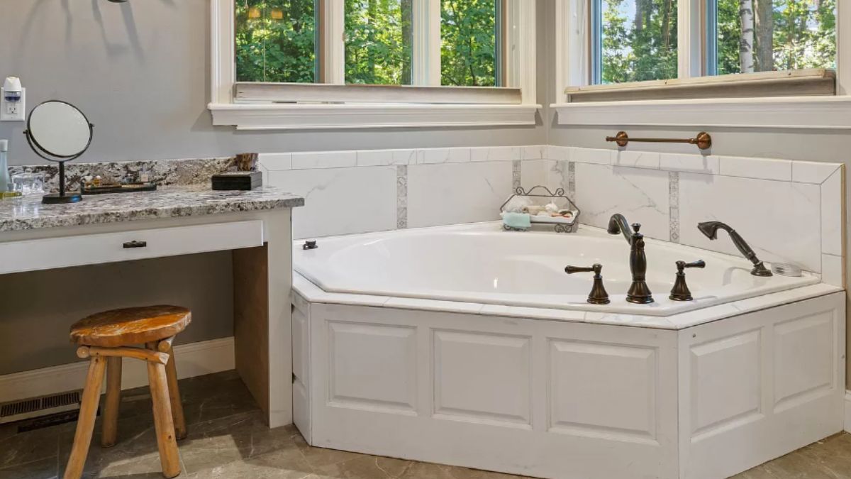 A bathroom with windows, countertop, chair, and bathtub.