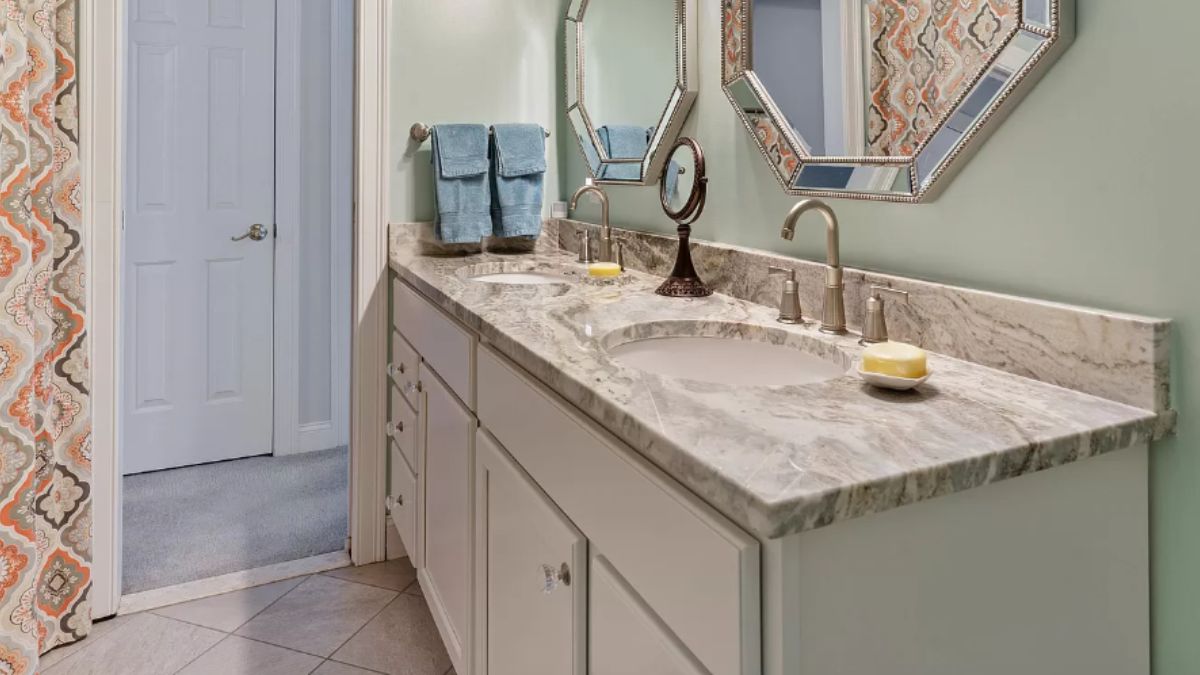 A bathroom with a vanity, mirrors, and cabinets.