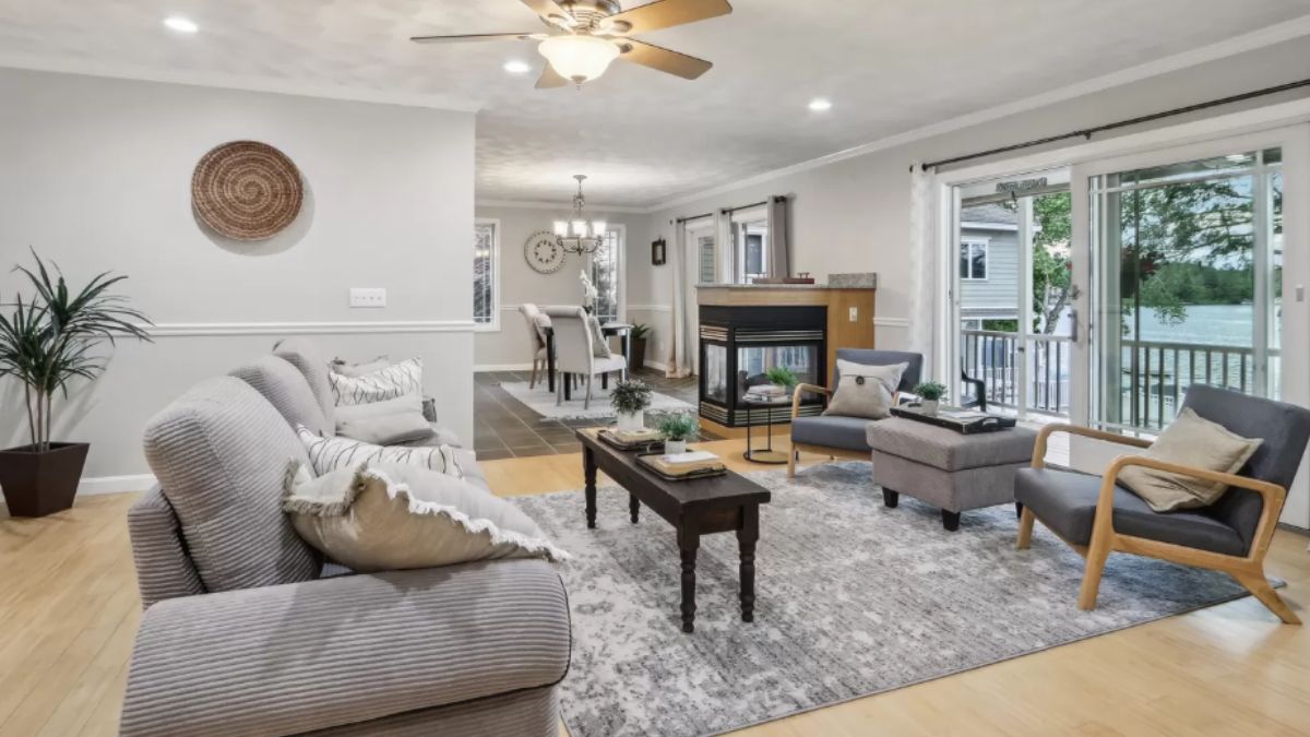 A living room with a ceiling fan, windows, couches, a rug, chairs, and a center table.