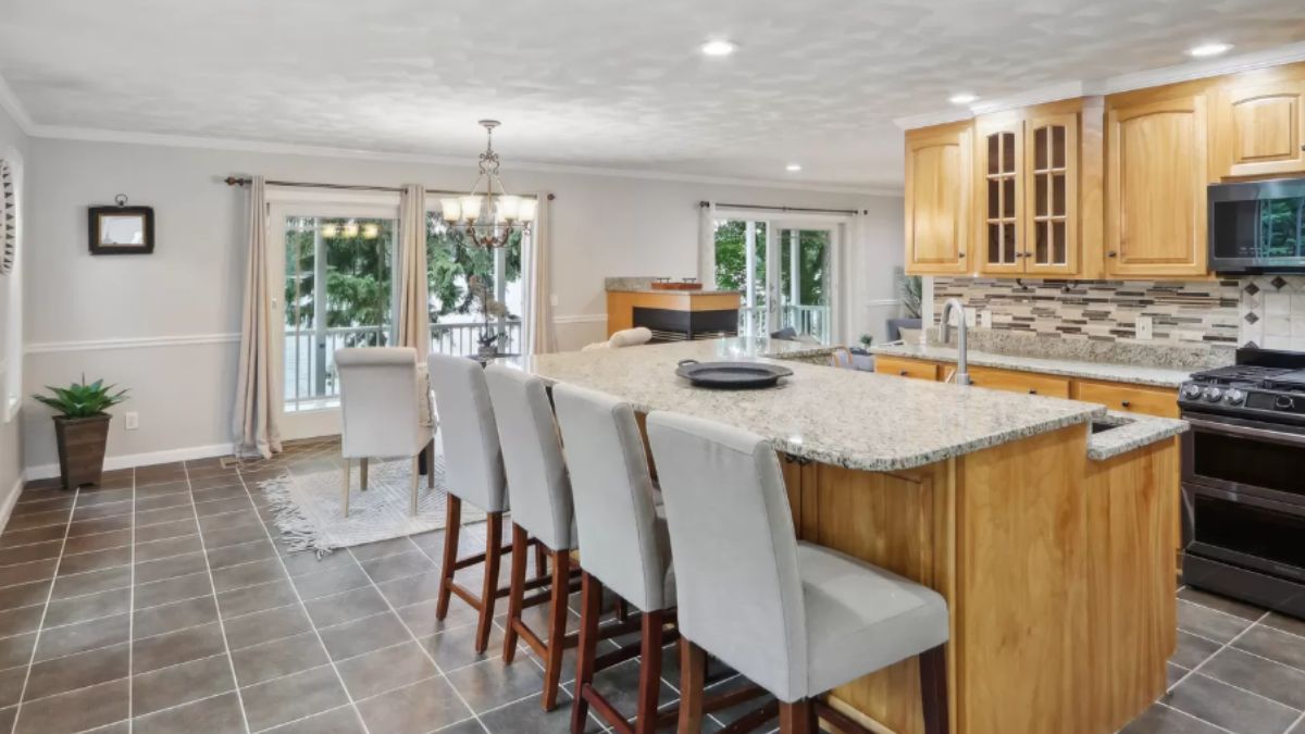 A kitchen with countertops, chairs, a sink, cabinets, and kitchen appliances.