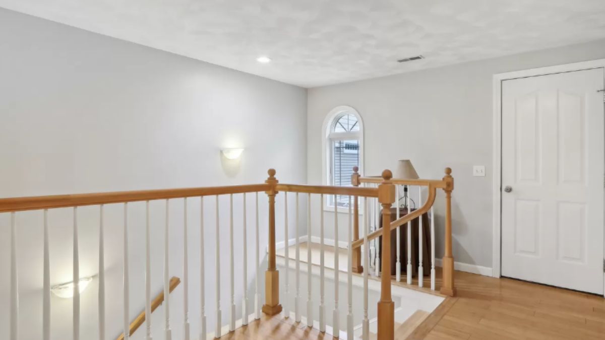 A landing with a wooden floor and wooden handrail.