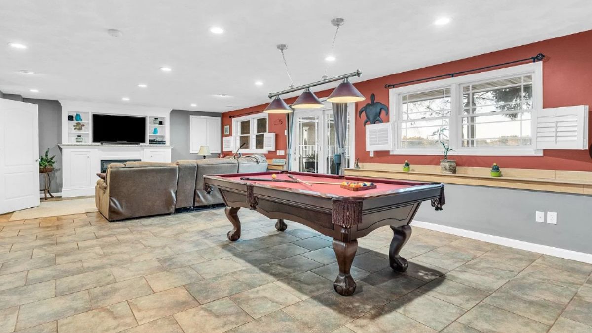 An entertainment room with a TV, couch, and pool table.