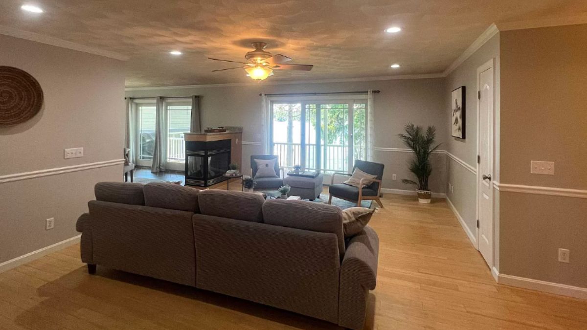 A living room with a ceiling fan, fireplace, chairs, and couch.