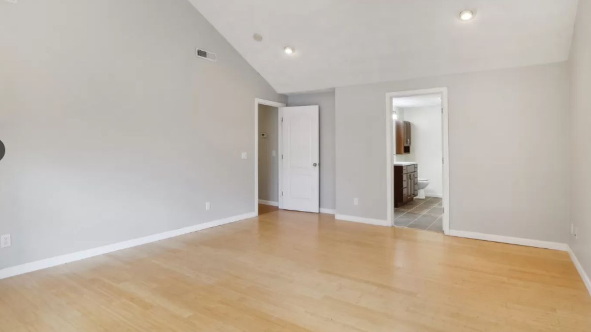 An empty bedroom with a wooden floor.