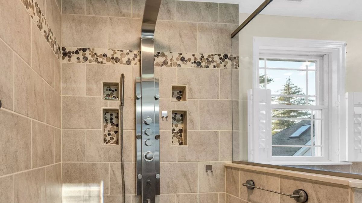 A bathroom with a shower room with tiled walls.