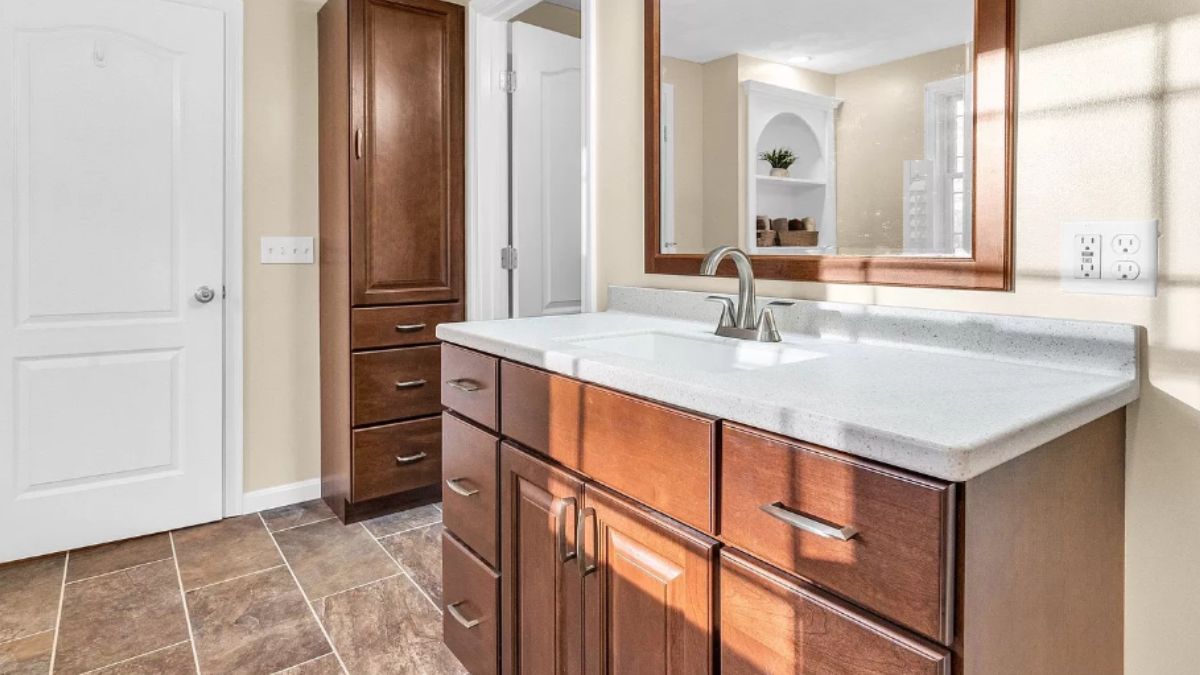 A bathroom with a vanity, cabinets, and mirror.