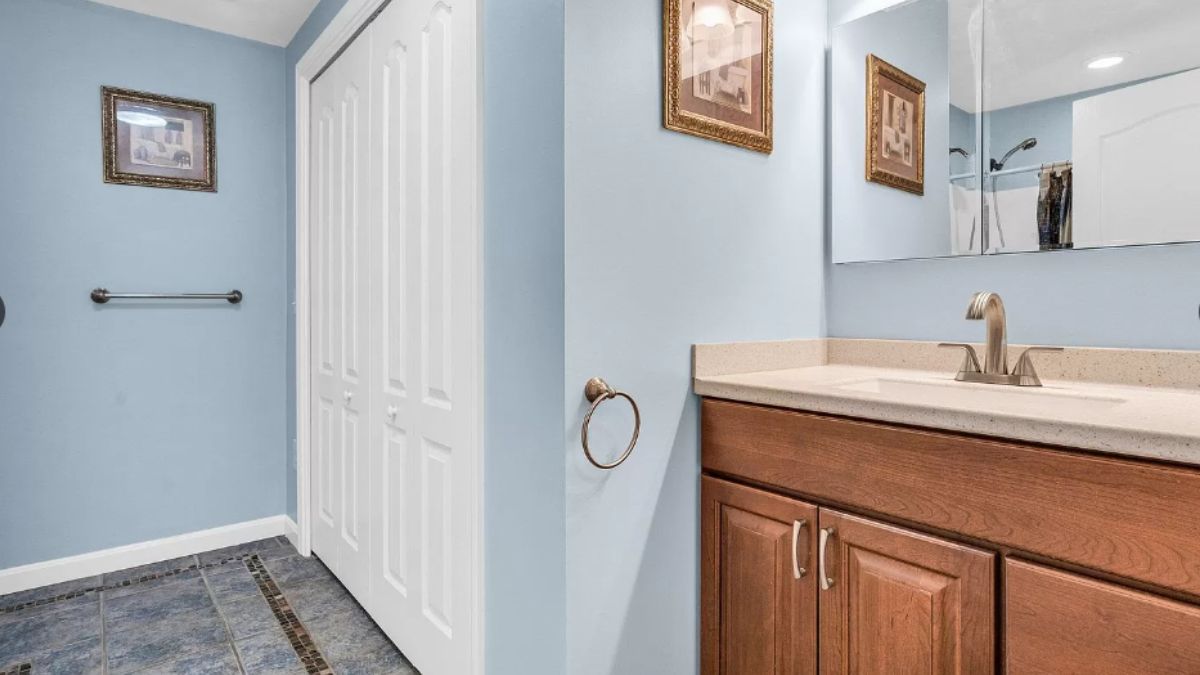 A bathroom with a vanity, cabinets, and mirror.