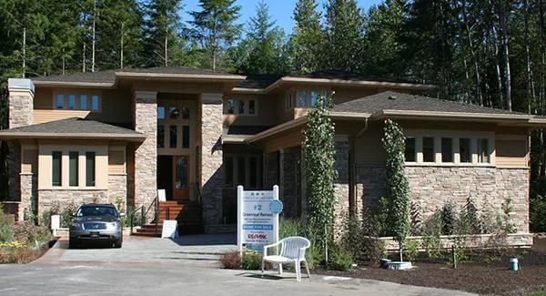 Front view with a multitude of windows, hipped rooflines, and a sleek entry.