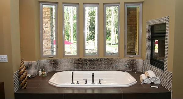 Primary bathroom showcasing a bathtub warmed by a fireplace.