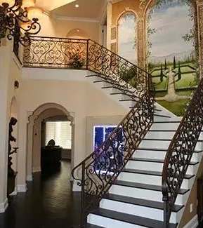 Foyer with a staircase framed with ornate railings.