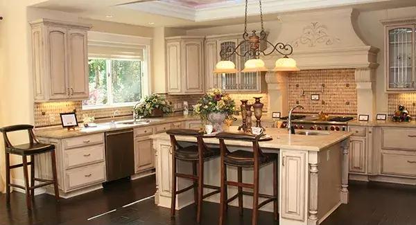 Kitchen with custom cabinetry and a large island illuminated by a warm chandelier.