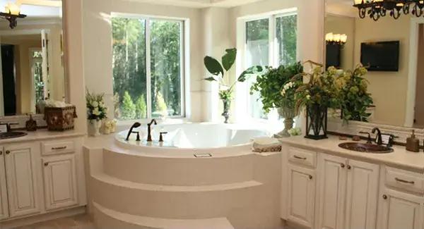 Primary bathroom with his and her vanities flanking the corner tub.