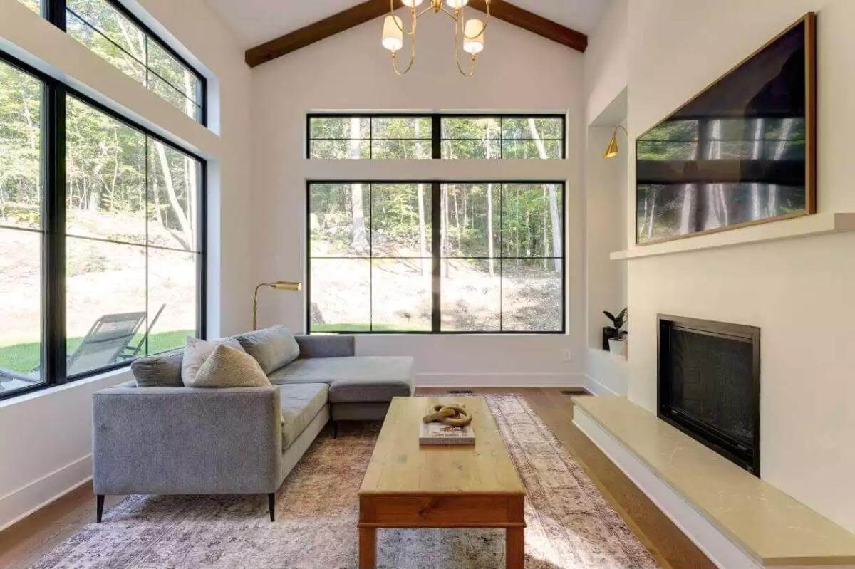 Living room with a fireplace, an L-shaped sofa, and a wooden coffee table under a vaulted ceiling.