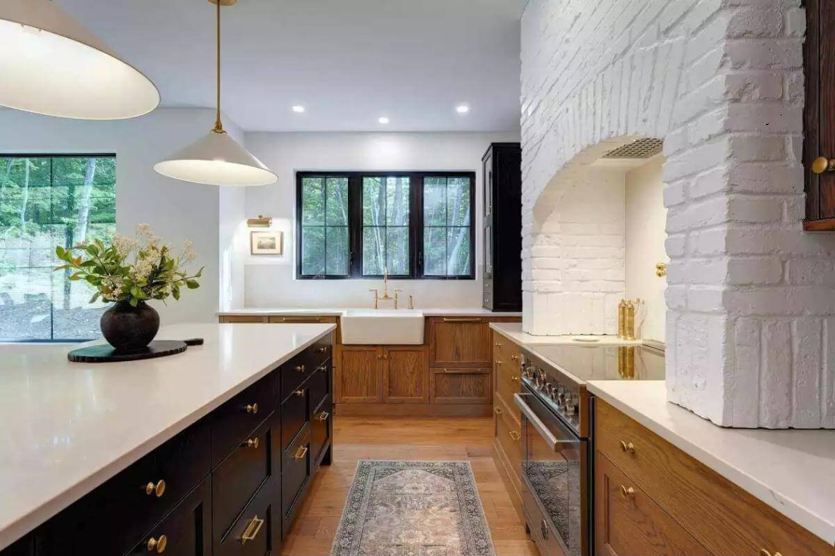 Kitchen with wooden cabinets, a farmhouse sink, and a large island illuminated by brass pendants.