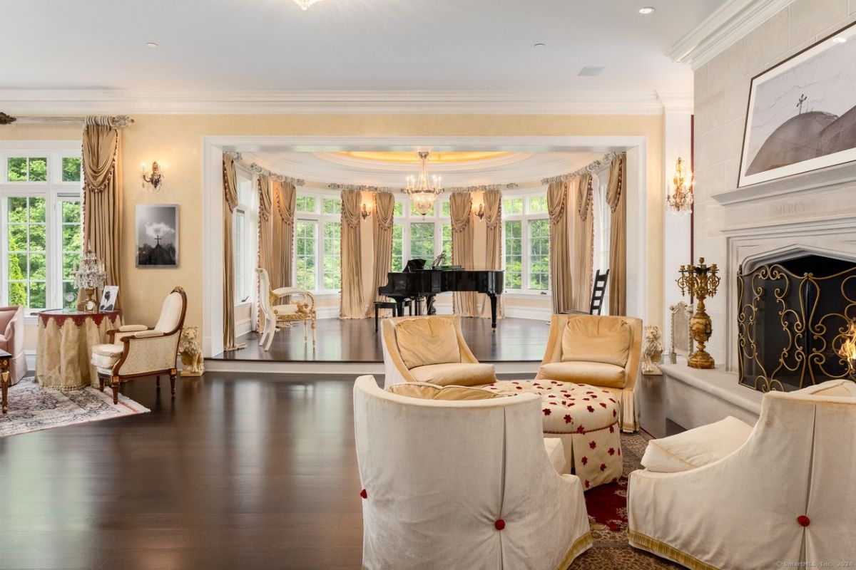 A living room with a fireplace, windows, a painting, chairs, and a coffee table.