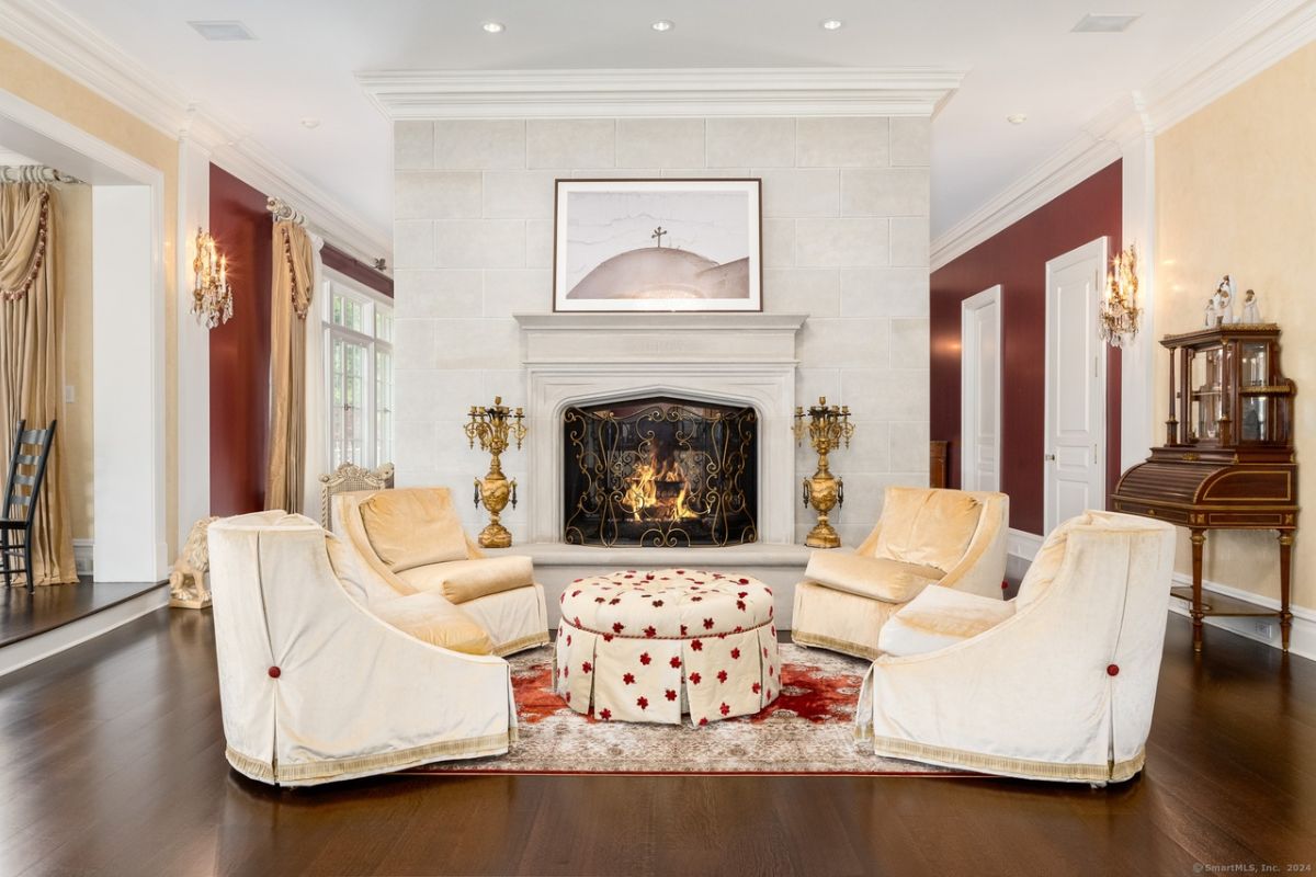 A living room with a painting, fireplace, and center table surrounded by chairs.