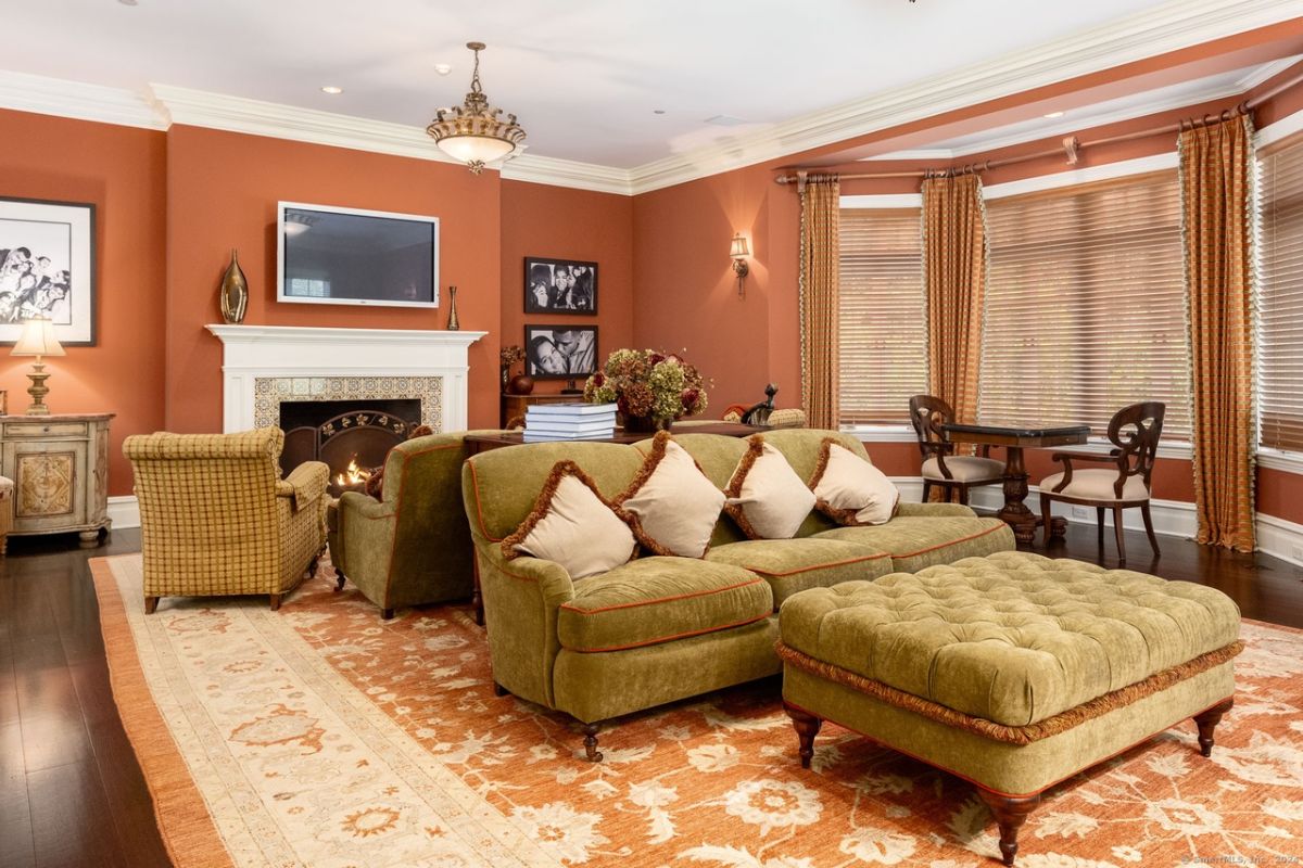 A family room with a TV, fireplace, rug, chairs, and couches.