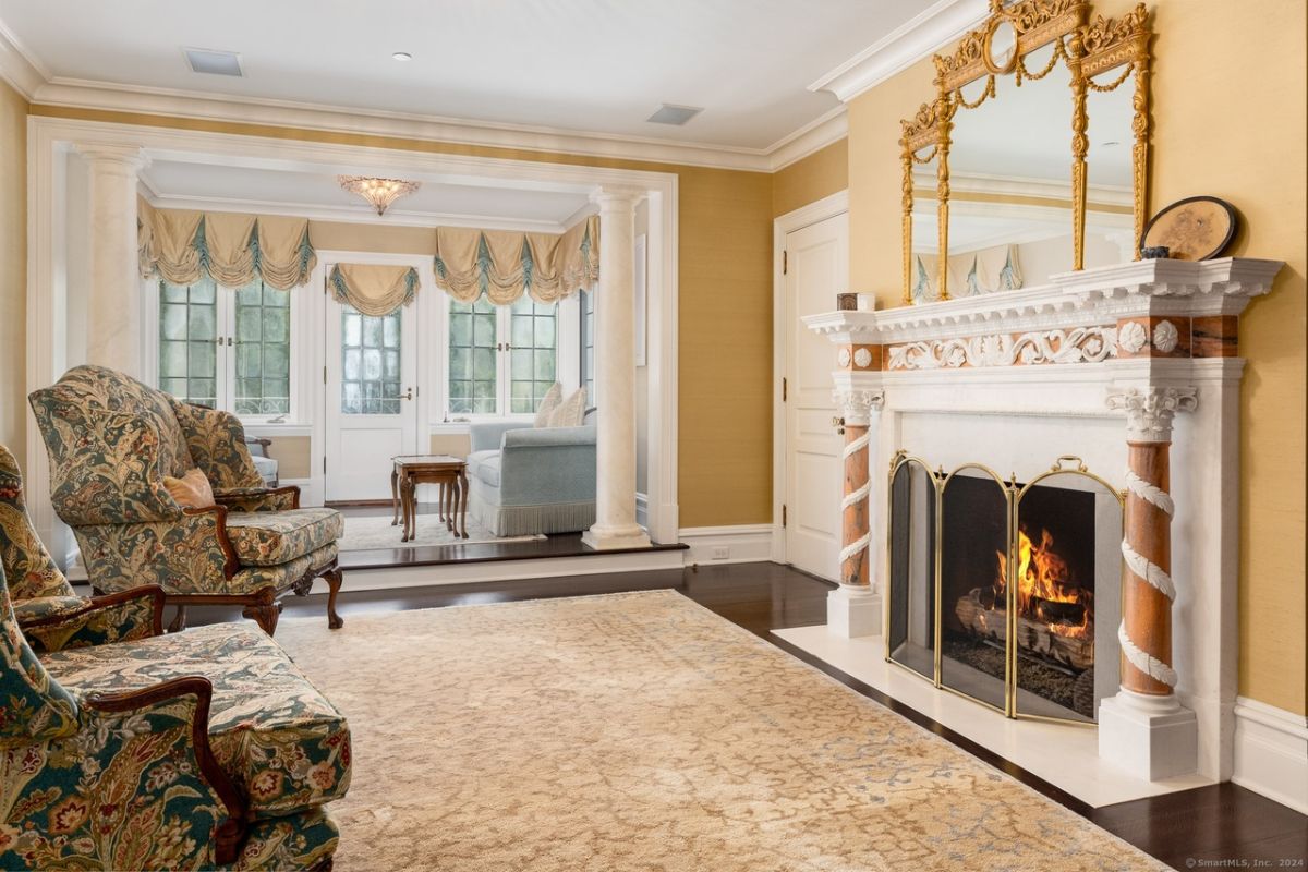 A family room with chairs, a mirror, and a fireplace.