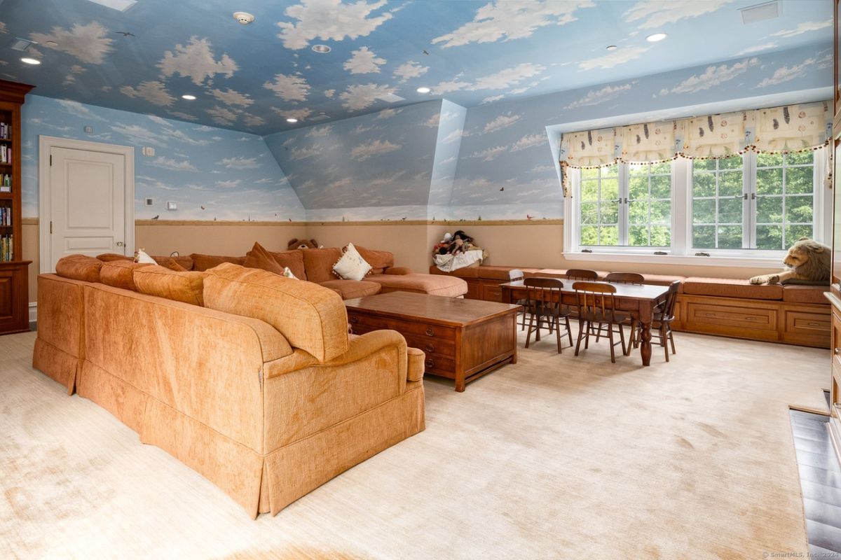 A family den painted walls, a painted ceiling, windows, window seating, tables, chairs, and couches.