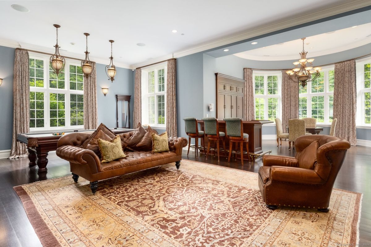 An entertainment room with a pool table, bar, rug, and couches.