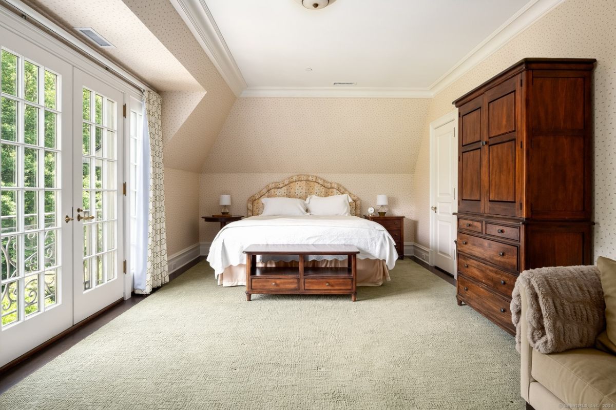 A bedroom with a bed, nightstands, windows, cabinets, and a couch.