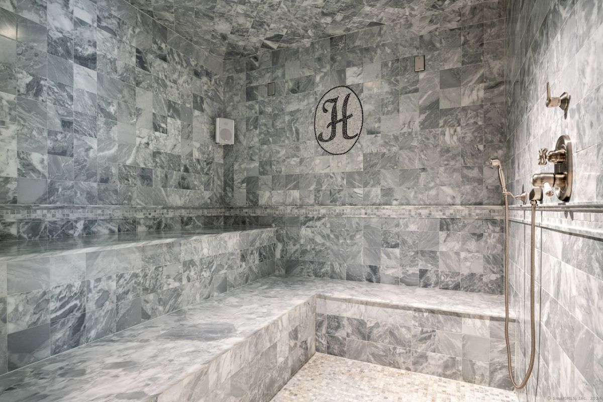 A bathroom with shower room with tiled walls and a tiled floor.