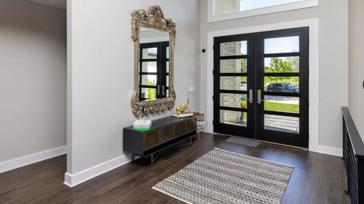 A foyer with a mirror, cabinet, and rug.