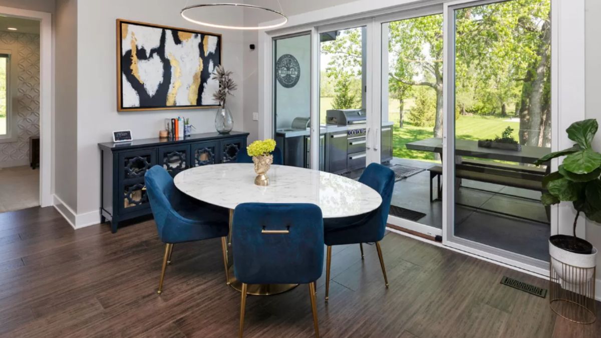 A dining room with a painting, cabinet, and round dining table surrounded by chairs.