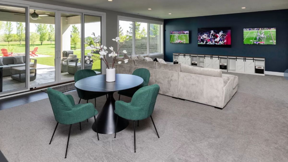 A family room with TVs, a couch, and a round table surrounded by chairs.