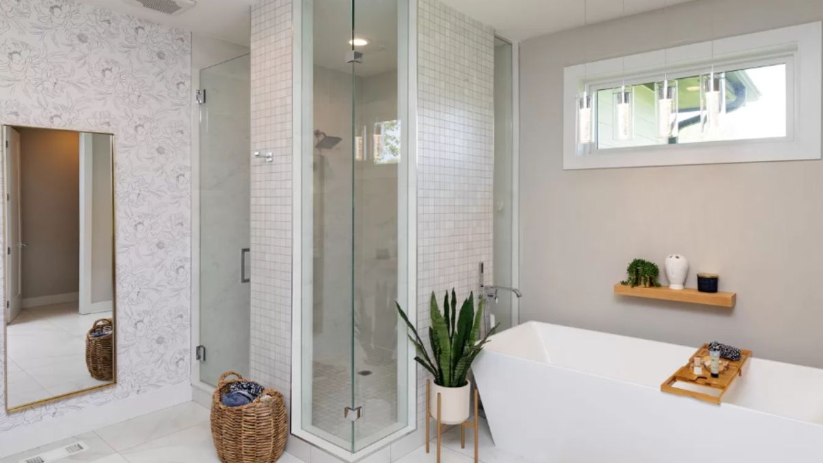 A bathroom with a mirror, window, bathtub, and shower room.