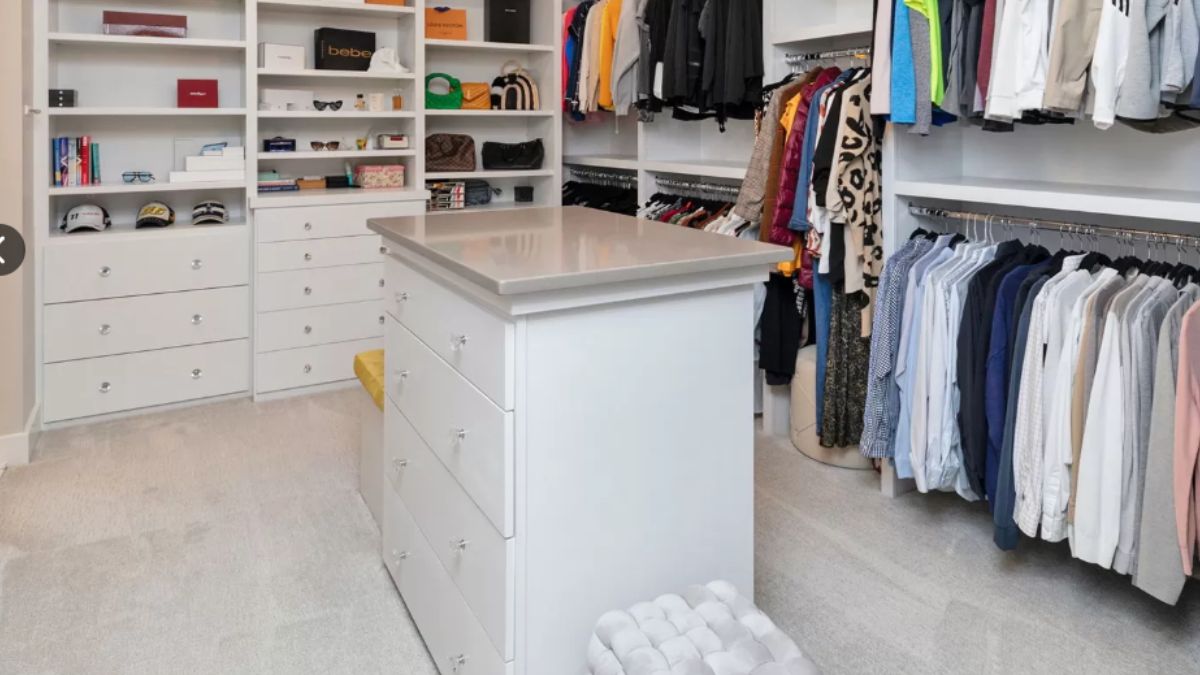 A walk-in closet with a center island, cabinets, and drawers.