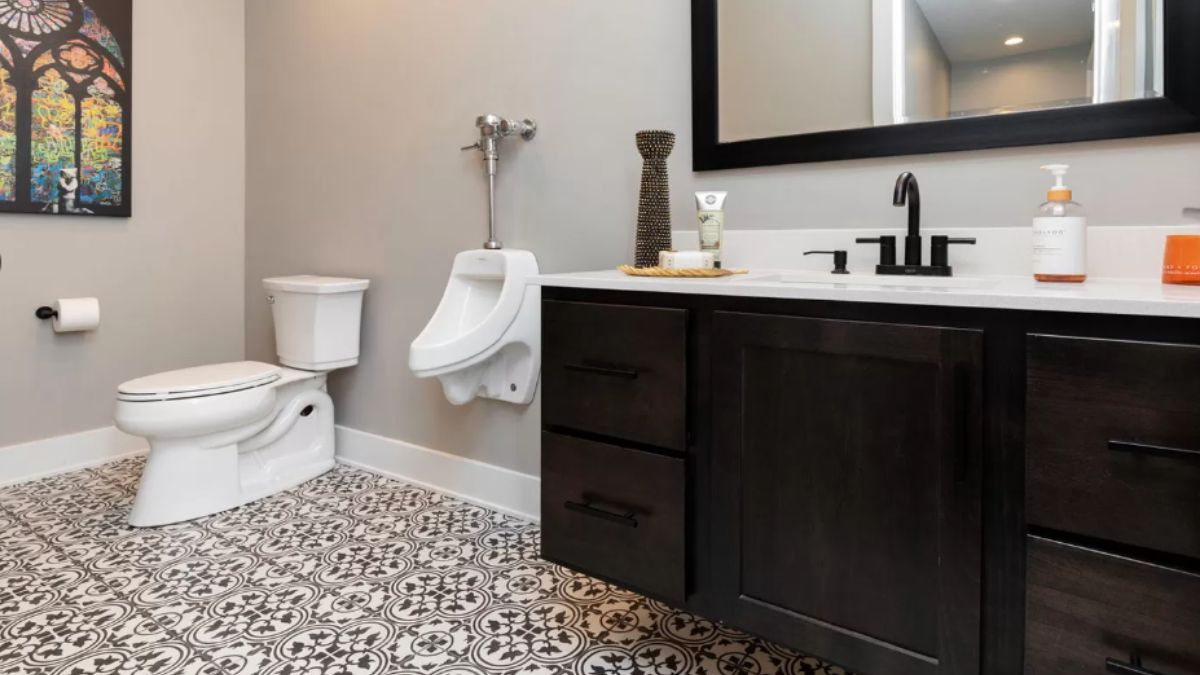 A bathroom with tiled floor, cabinets, vanity, mirror, and toilet.