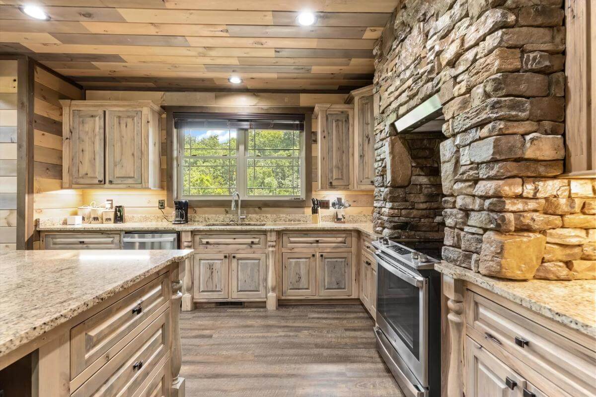 The kitchen includes a stone alcove cooking and a prep sink under the wooden-framed window.