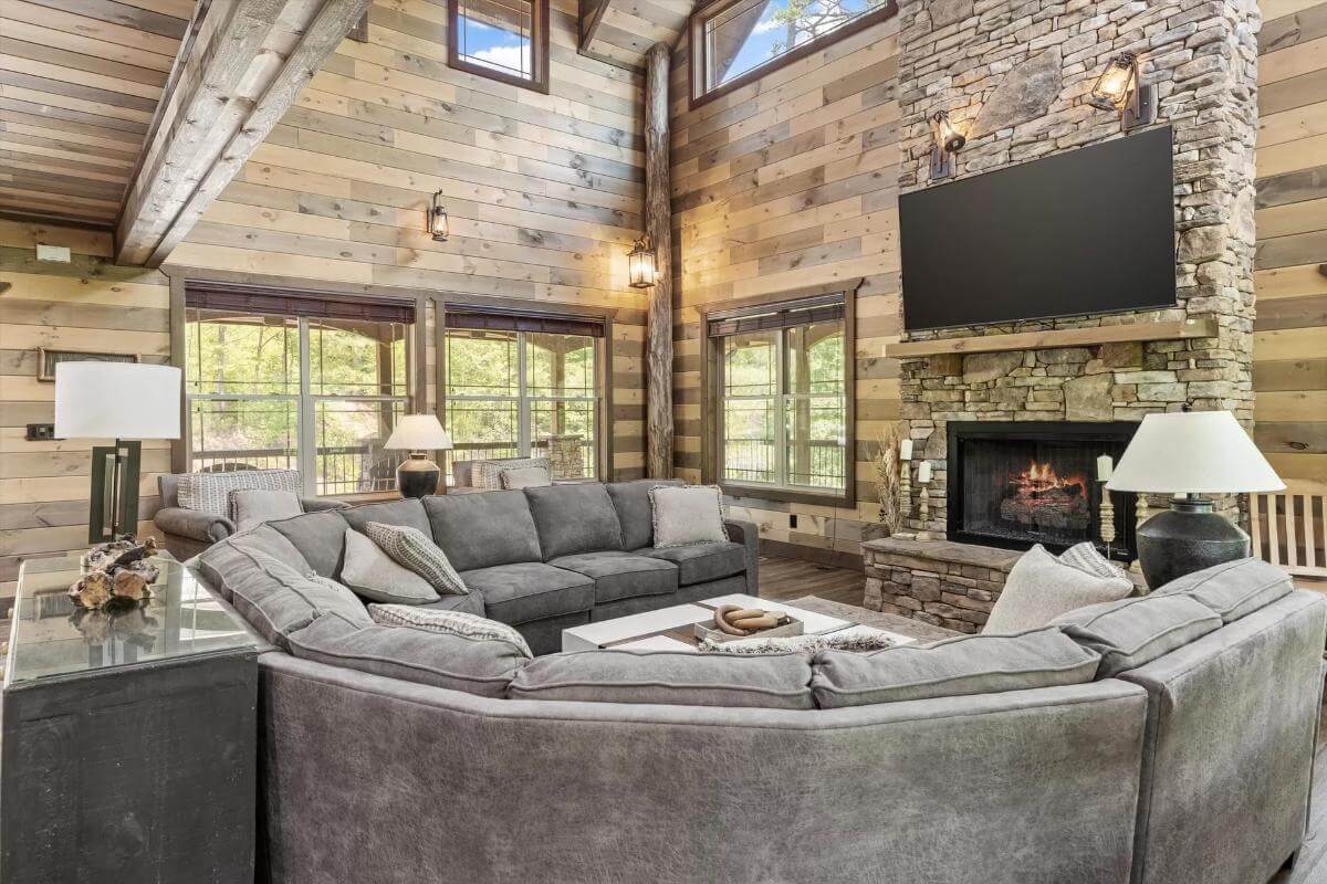 Living room with a curved sectional sofa and a large TV fixed above the stone fireplace.