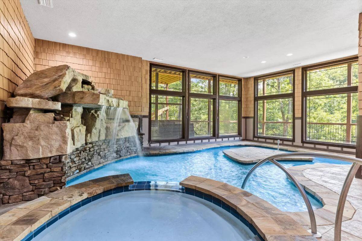 Indoor pool with a built-in spa and a waterfall feature.