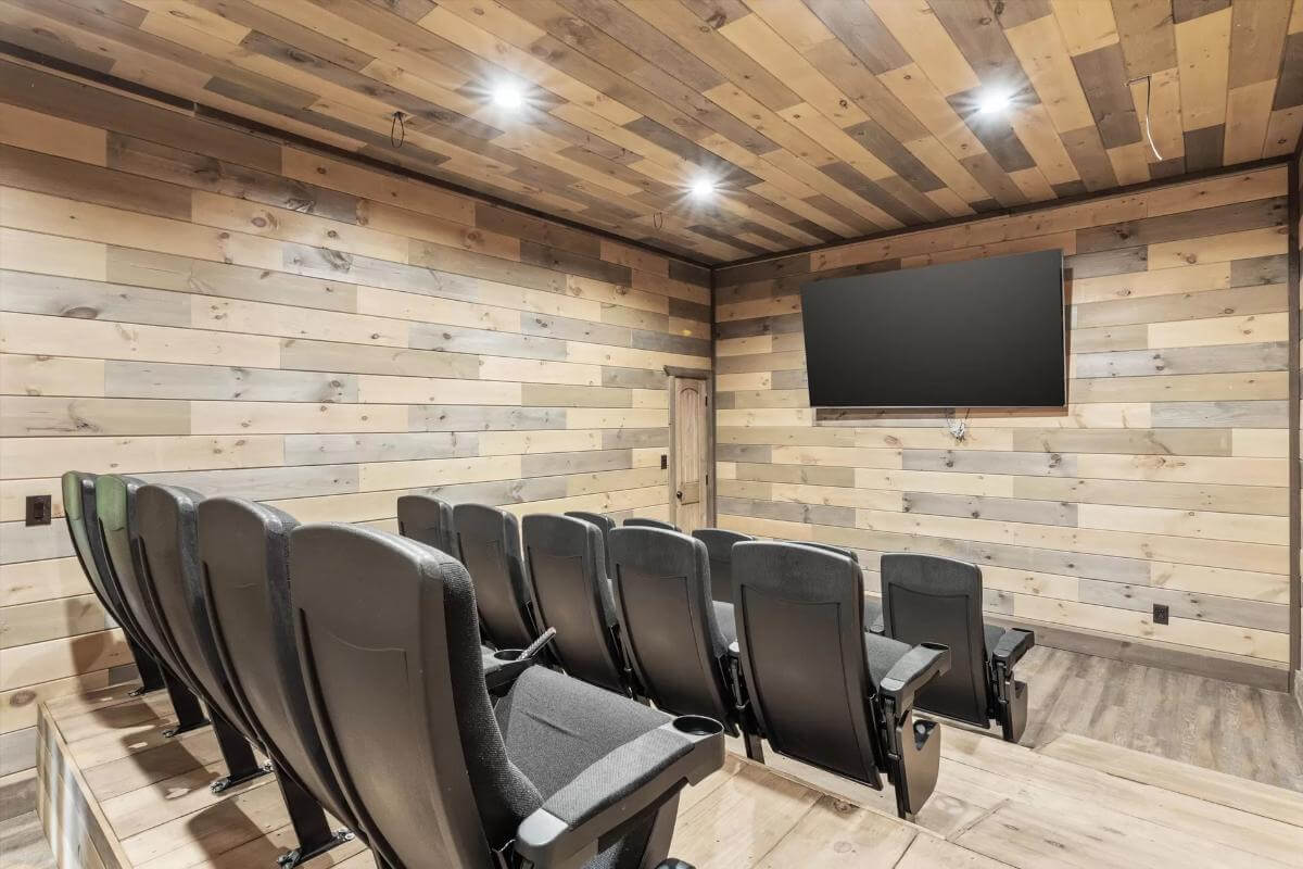 Movie room with black recliners and a large wall-mounted TV.