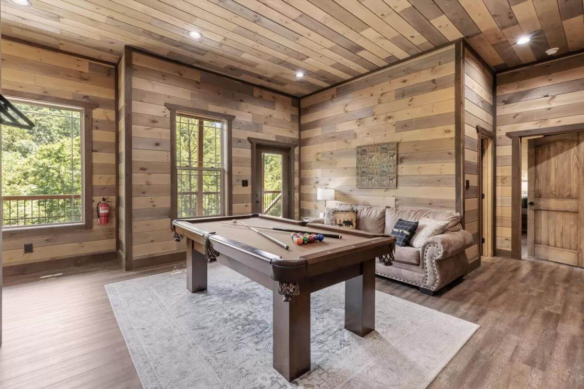 Game room with a velvet sofa and a billiards table over the distressed area rug.