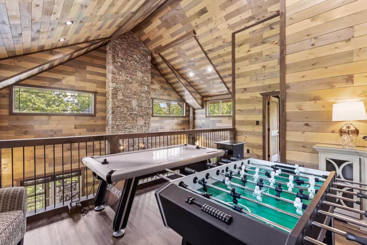 Entertainment loft with various game tables under a vaulted ceiling.