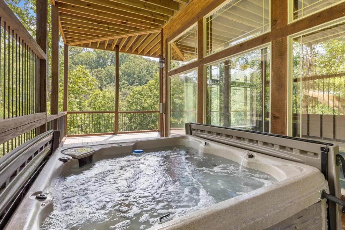 Covered deck with a hot tub under a beamed ceiling.