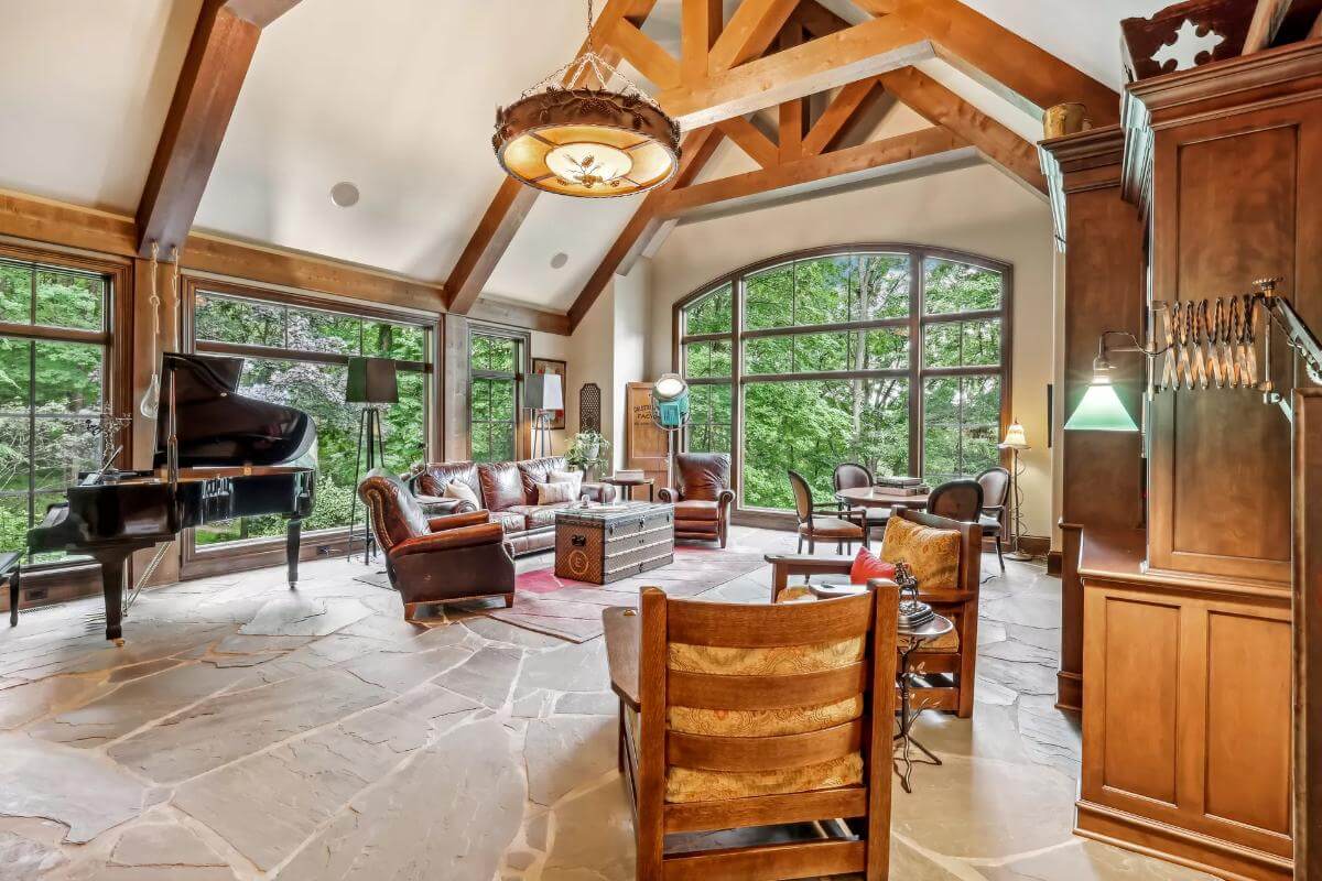 Family room with leather seats, a grand piano, and a cathedral ceiling adorned with exposed trusses.