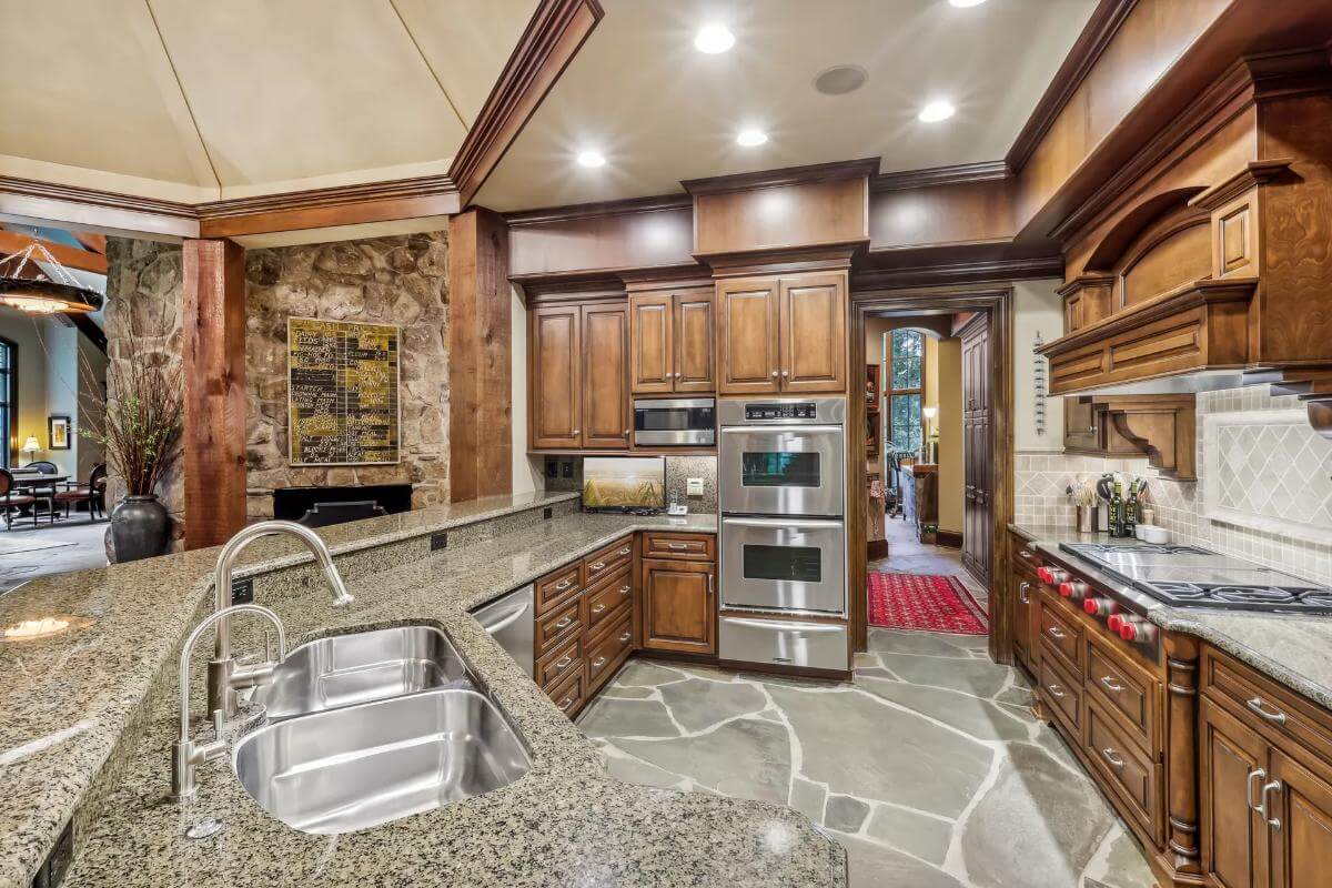 Kitchen with dark wood cabinets, double wall ovens, and an angled peninsula with a raised eating bar.