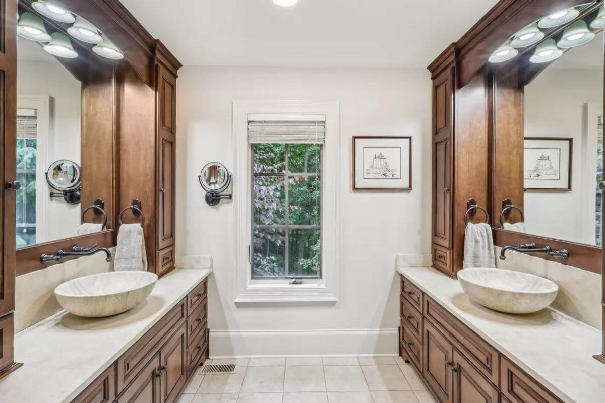 His and her vanities with wooden cabinets and vessel sinks.