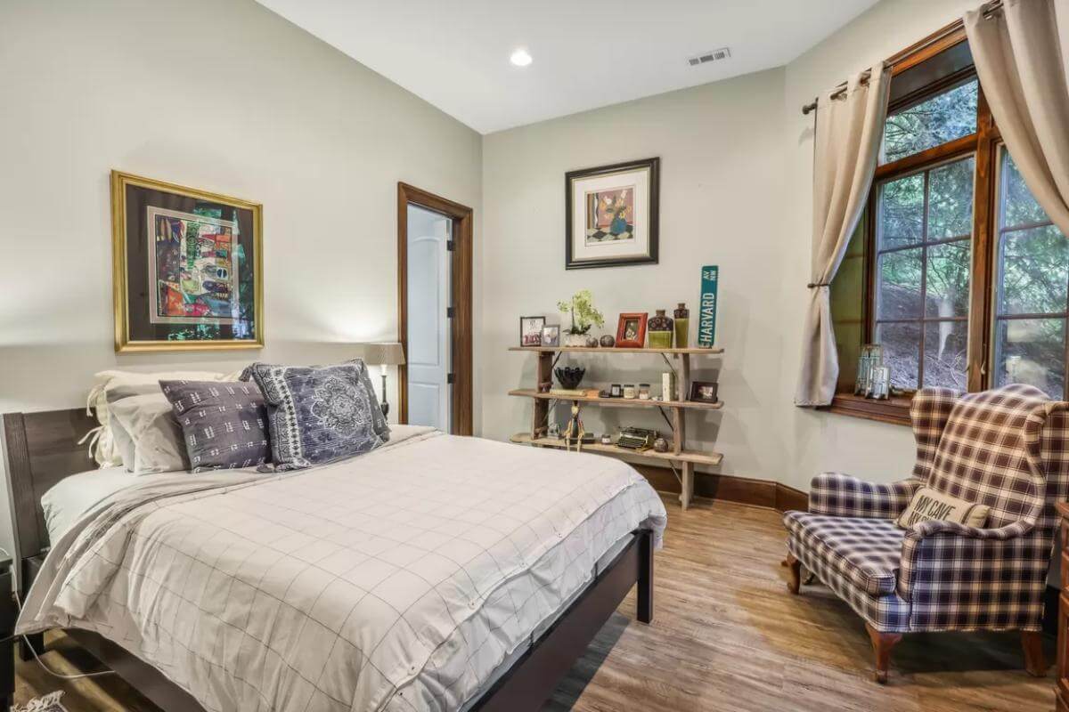 Bedroom with a dark wood bed and a checkered wingback chair over the hardwood flooring.