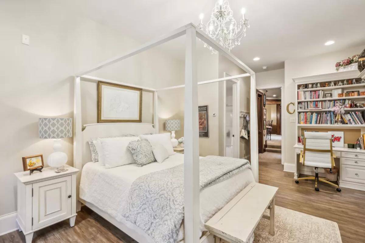 Bedroom  with a canopy bed and a white desk integrated with a bookshelf.